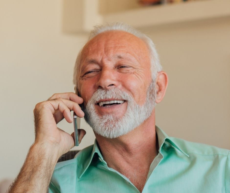 férfi mosolyogva telefonál zöld ingben